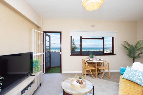 una sala de estar con un televisor y una mesa en Beach Front Retreat in Fish Hoek, en Fish Hoek