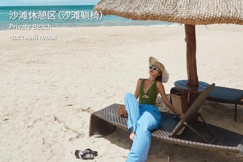 a woman sitting on a chair on the beach at MGM Grand Sanya in Sanya