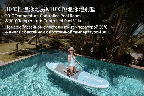 Eine Frau fährt auf einem Paddleboard in einem Schwimmbecken in der Unterkunft MGM Grand Sanya in Sanya