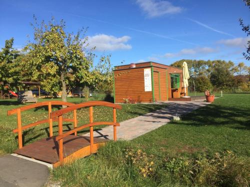 un banc en bois dans un parc avec un bâtiment dans l'établissement Weihersmühle, à Fladungen
