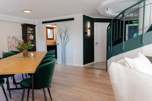 een eetkamer met een tafel en groene stoelen bij Villa Octogon Câmpina in Campina