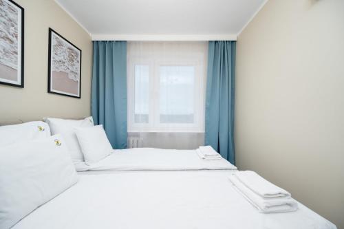 a large white bed in a room with a window at Apartament Baltic Panorama ProstyWynajem Parking in Zaspa