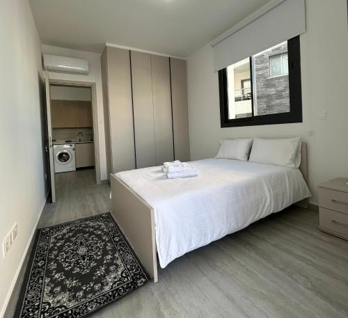 a bedroom with a large white bed and a kitchen at AFRODITI Living in Nicosia