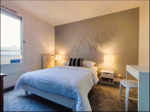 ein Schlafzimmer mit einem großen weißen Bett und einem Fenster in der Unterkunft Le Duplex du Marche-centre-parking prive-balcon in Châteauroux