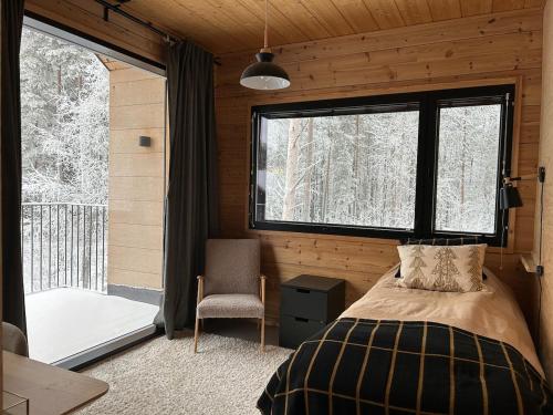 a bedroom with a bed and a window and a chair at Hulppea merenranta hirsitalo in Oulu