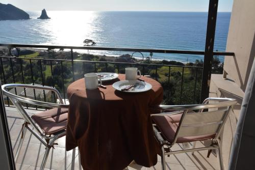 a table on a balcony with a view of the ocean at Sunny views studios in Agios Gordios