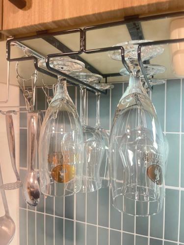four wine glasses hanging from a rack in a kitchen at Stay Narimasu - 3rooms Apartment, 4min to Narimasu station, 1min to Donki in Tokyo