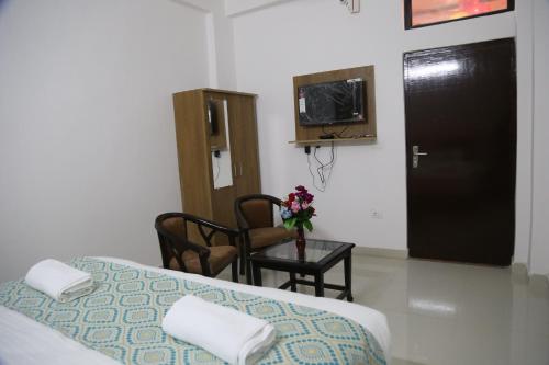 a bedroom with a bed and a table with a vase of flowers at Hotel Yog Tapovan in Rishīkesh