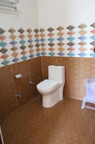 a bathroom with a toilet and a tiled wall at Hotel Yog Tapovan in Rishīkesh