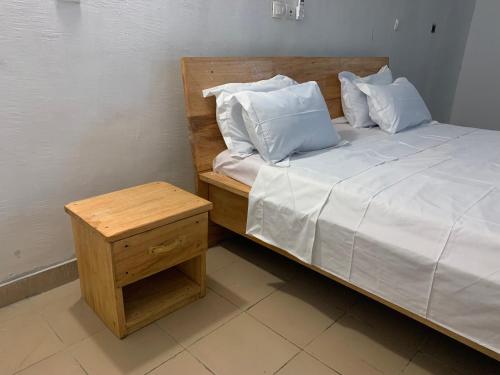 een bed met witte lakens en kussens naast een tafel bij Lege Bonoua in Bonoua