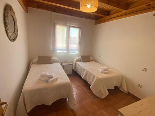 a room with two beds with white sheets and a window at La espiga de Segovia 2 in La Lastrilla