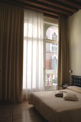 a bedroom with a bed and a large window at Albergo al Tiepolo in Venice