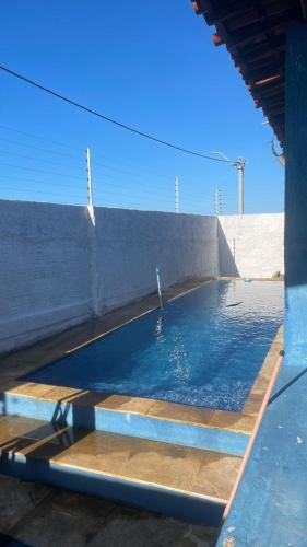 a swimming pool with blue water in front of a wall at Casa de Praia in Caucaia