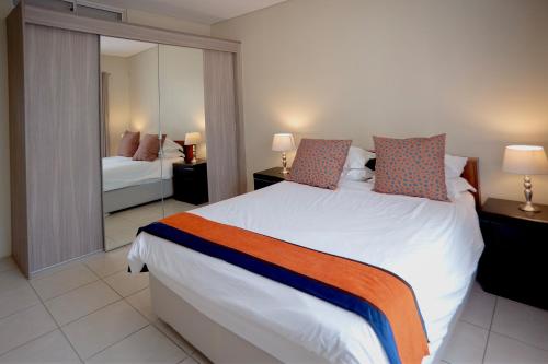 Un dormitorio con una gran cama blanca y un espejo. en Apartments @ 125, en Gaborone