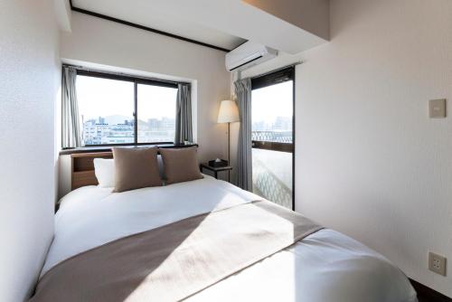 a bedroom with a bed and a large window at AMP FLAT MOMOCHi in Fukuoka