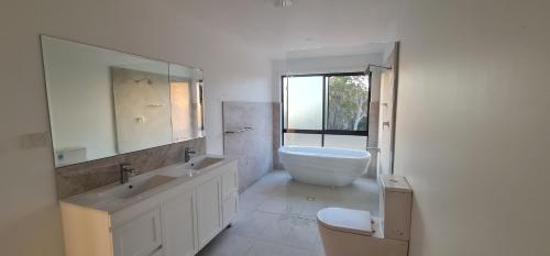 a white bathroom with a sink and a toilet at Redhill Batemans Bay in Batemans Bay