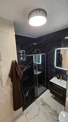 a bathroom with a glass shower and a sink at GOLD APARTAMENT Ząbki in Ząbki