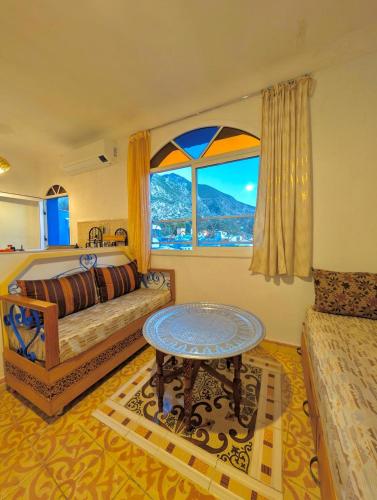a bedroom with a bed and a table and a window at DAR Dunia Panoramic terrace in Chefchaouen