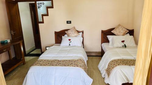 Zimmer mit 3 Betten mit weißer Bettwäsche und Blumen in der Unterkunft Luxstay kochi in Kochi