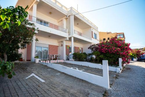 a large building with flowers in front of it at Blife Petrya private rooms at Faro beach in Faro