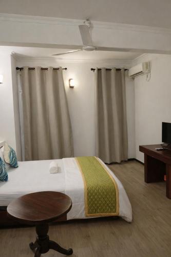 a bedroom with a bed and a table and curtains at Male City Stay in Male City
