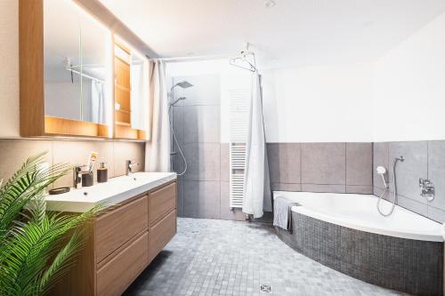a bathroom with a tub and a sink and a bath tub at Weinblick Sauna-Infrarot 2 Schlafzimmer in Saarburg