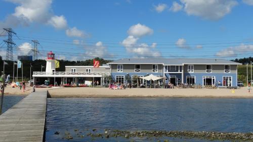 a building on the beach with a lighthouse in the background at Beach Hotel Oostvoorne in Oostvoorne