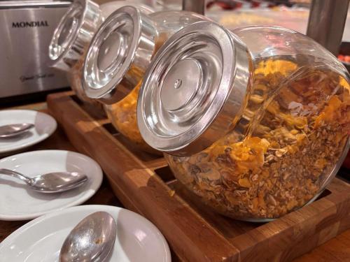 a group of jars of food on a wooden tray with spoons at ibis Styles Confins Aeroporto in Lagoa Santa