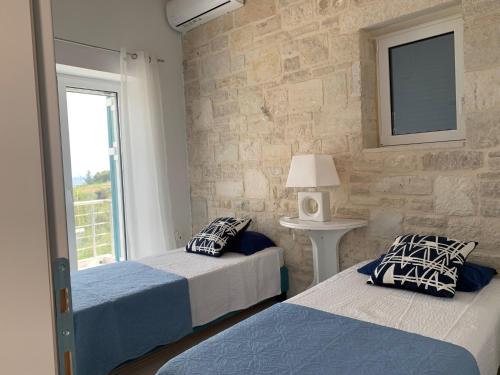 2 letti in una camera da letto con parete in pietra di villa Elaionas a Tsivarás
