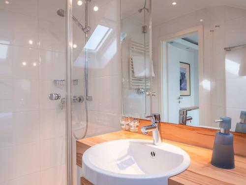 Un baño blanco con lavabo y ducha. en Miramar, en Helgoland