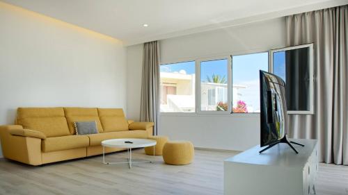 sala de estar con sofá amarillo y TV en Deva Beach Boutique Apartments, en San Fernando