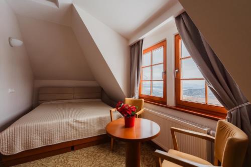 Un dormitorio con una cama y una mesa y una ventana. en Hotel VÍTKOVA HORA, en Karlovy Vary