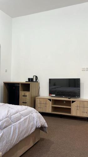 a bedroom with a bed and a flat screen tv at Khalifa A Home Stay NR in Abu Dhabi