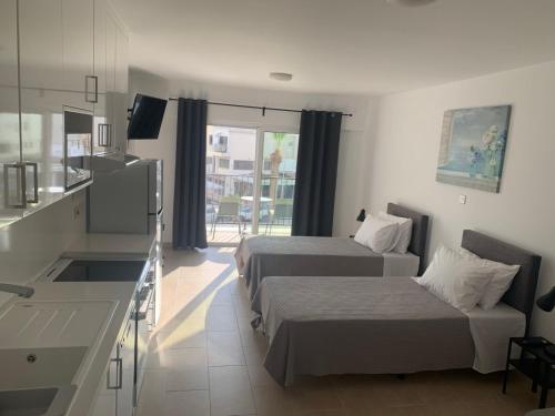 a hotel room with two beds and a kitchen at Rimini Balcony Studios - Steps from the Sea in Paphos