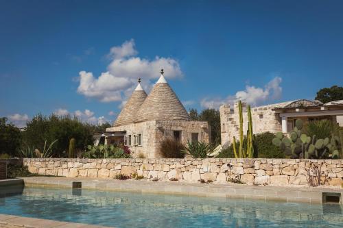 a resort with a stone wall and a swimming pool at Regina di Ulivi in Ostuni