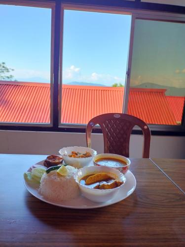 a plate of food sitting on a wooden table at Kanchenjunga Vista Pabong in Sāmthar