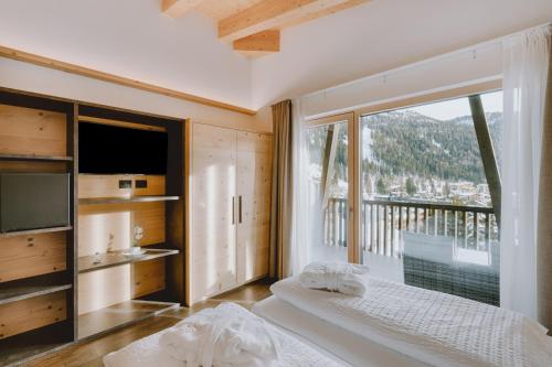 a bedroom with a bed and a large window at Alpen Hotel Vidi in Madonna di Campiglio