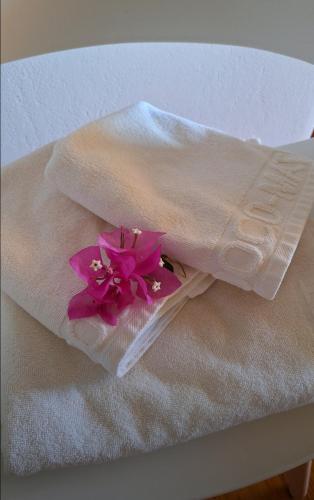 Ein weißes Handtuch mit rosa Blumen liegt auf einem Bett. in der Unterkunft Sail in in Drios