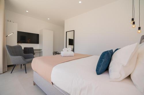 een slaapkamer met een groot wit bed en een stoel bij Sirius House in Guia