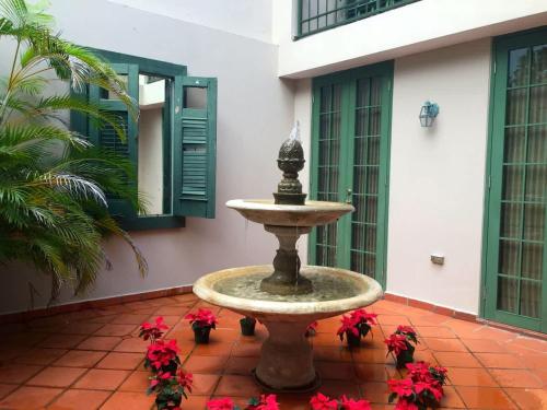 a fountain in the courtyard of a building with red flowers at Villa Arrecife Community Pool w Ocean View in Dorado