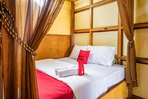 een bed in een kamer met een rood kussen erop bij RedDoorz near Kawah Putih Ciwidey in Bandung