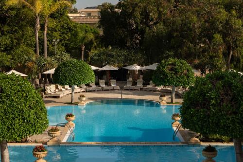 a large blue pool with chairs and umbrellas at Corinthia Palace Malta in Attard