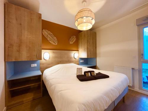 ein Schlafzimmer mit einem großen weißen Bett und einem Kronleuchter in der Unterkunft L'Oranger bleu in Royan