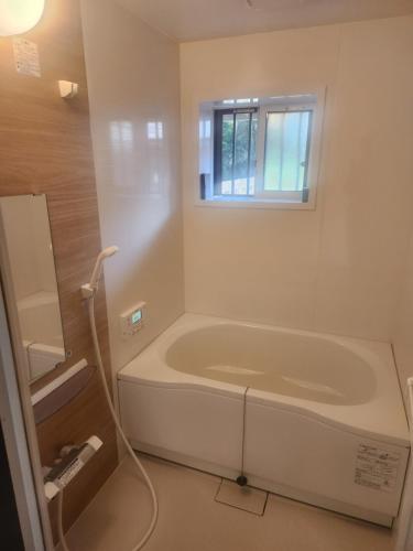 uma banheira branca em um banheiro com janela em 古民家宿懐 em Nachikatsuura