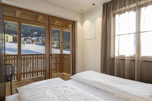 a bedroom with a bed and a balcony at Tieja Panoramic Lodge in Selva di Val Gardena