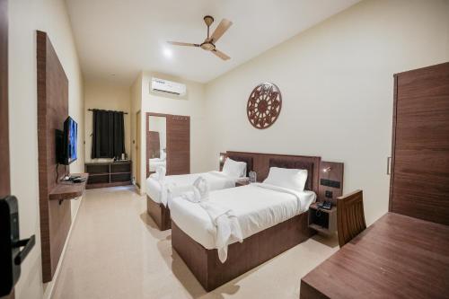 a bedroom with two beds and a flat screen tv at Kayalresidency in Gopichettipālaiyam
