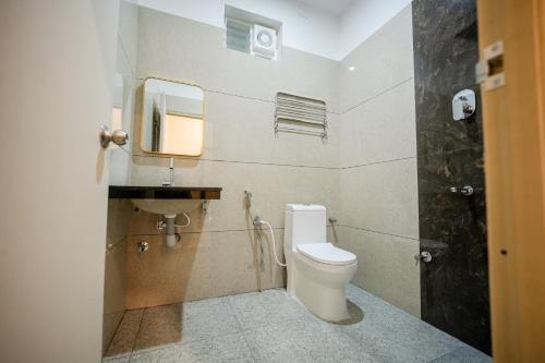 a bathroom with a toilet and a sink and a mirror at Kayalresidency in Gopichettipālaiyam
