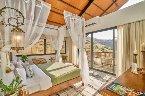 a bedroom with a bed and a large window at SaffronStays Villa Reya in Trimbak