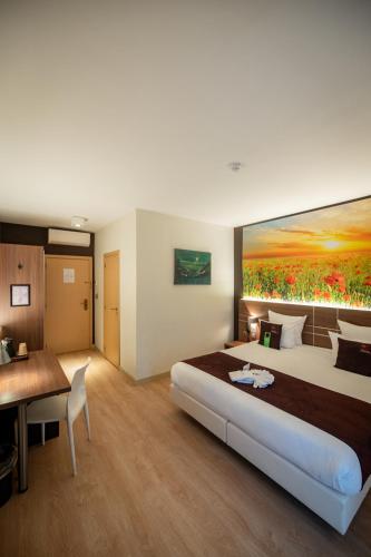 a bedroom with a large bed with a painting on the wall at Hotel-Restaurant Horizon Ath-Lessines in Ghislenghien