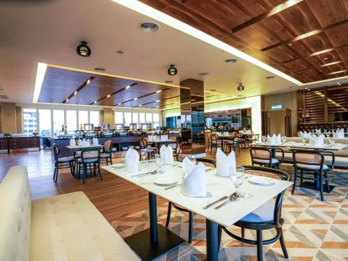 a dining room with tables and chairs in a restaurant at Mercure Langkawi Pantai Cenang in Pantai Cenang